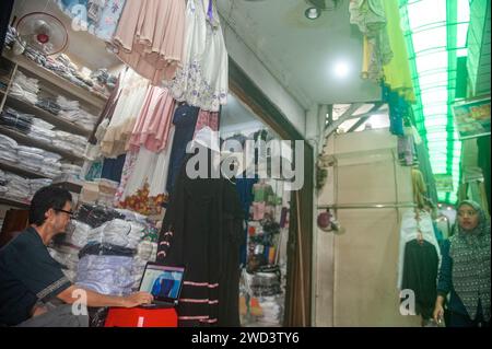 Indonesien. Januar 2024. Ein Textilhändler wurde am 18. Januar 2024 bei Mutiara Deli, einem muslimischen Modegeschäft im Bekleidungshandelsgebiet Pasar Ikan in Medan City, Provinz Nord Sumatra, Indonesien, beobachtet. Die Nutzung von Website-Diensten für den elektronischen Handel ist bei Geschäftsleuten immer beliebter geworden, da sie Verkehrsstaus überwinden und Marketingkosten im nachhaltigen Handel senken können. Foto: Sutanta Aditya/ABACAPRESS.COM Credit: Abaca Press/Alamy Live News Stockfoto