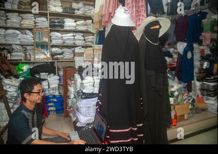 Indonesien. Januar 2024. Ein Textilhändler wurde am 18. Januar 2024 bei Mutiara Deli, einem muslimischen Modegeschäft im Bekleidungshandelsgebiet Pasar Ikan in Medan City, Provinz Nord Sumatra, Indonesien, beobachtet. Die Nutzung von Website-Diensten für den elektronischen Handel ist bei Geschäftsleuten immer beliebter geworden, da sie Verkehrsstaus überwinden und Marketingkosten im nachhaltigen Handel senken können. Foto: Sutanta Aditya/ABACAPRESS.COM Credit: Abaca Press/Alamy Live News Stockfoto