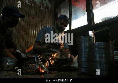 18. Januar 2024, Srinagar Kashmir, Indien: Ein Koch serviert Harissa an einem kalten Morgen in Srinagar. Harissa ist ein einzigartiges uraltes Hammelrezept, das während der Winter in Kaschmir zubereitet wird. Es ist meistens in den Morgenstunden aus Hammelfleisch, besonders von Schafen, erhältlich. Das Hammelfleisch wird zuerst bei milder Temperatur gekocht und alle Knochen werden extrahiert, um es entbeint zu machen. Das Hammelfleisch wird dann mit Reismehl, Wasser und verschiedenen Gewürzen gemischt und ständig umgerührt, bis es quaschig wird. Die Leute mögen dieses Gericht meistens mit gebackenem Brot. Am 18. Januar 2024 In Srinagar Kaschmir, Indien. (Foto Von Firdous Naz Stockfoto