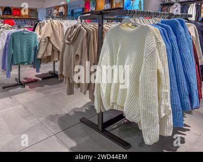 Pullover und Pullover für Frauen in verschiedenen Formen und Farben auf der Wäscheleine im Bekleidungsgeschäft Stockfoto