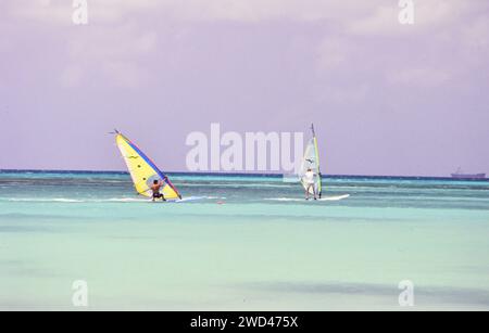 Lange Aufnahme von zwei Windsurfern (Boardsailern), die in den blauen Gewässern vor Aruba CA überquerten. Anfang der 1990er Jahre Bitte schreiben Sie dem Fotografen Joan Iaconetti zu Stockfoto