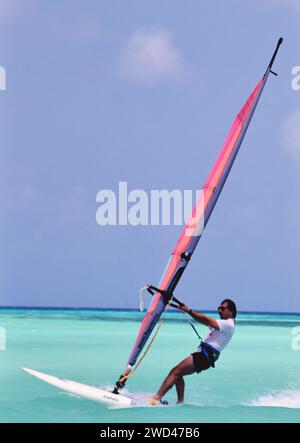 Junger Mann Windsurfen (Boardsegeln) im blauen Wasser vor Aruba CA. Anfang der 1990er Jahre Bitte schreiben Sie dem Fotografen Joan Iaconetti zu Stockfoto