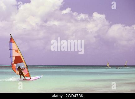 Junger Mann Windsurfen (Boardsegeln) im blauen Wasser vor Aruba CA. Anfang der 1990er Jahre Bitte schreiben Sie dem Fotografen Joan Iaconetti zu Stockfoto