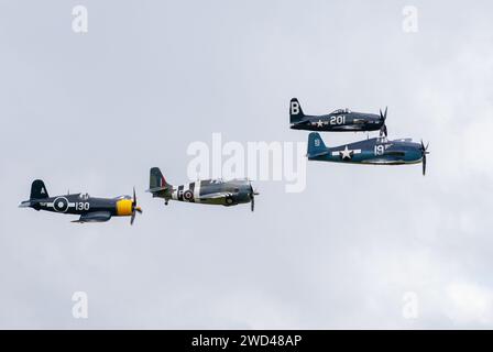 Amerikanische Kampfflugzeuge aus dem 2. Weltkrieg fliegen in enger Formation am Himmel. F4U Corsair, F8F Wildcat, F4F u. a. Stockfoto