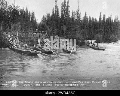 Eine Fotografie von Frachtschleusen mit flachem Boden aus dem Jahr 1901, die von C W Mathers auf einer Expedition in den hohen Norden Kanadas aufgenommen und in seinem Buch „The Far North“ veröffentlicht wurden. Mathers unterzeichnete dieses Foto: „Beladen der Boote nach der dritten Portage, Slave River. Mehl hier ist 10 Pfund Wert. Stockfoto