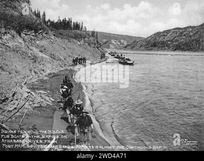 Ein 1901 erschienenes Foto von den Pelzbooten der Hudson’s Bay Company, das flussaufwärts auf dem Athabasca River (Alberta) gezogen wurde und von C W Mathers auf einer Expedition in den hohen Norden Kanadas aufgenommen und in seinem Buch „The Far North“ veröffentlicht wurde. Mathers untertitelte dieses Foto: Indians [First Nations People] verfolgen die H.B.C’so. Pelzboote die Stromschnellen auf dem Athabasca River hinauf, von Fort McMurray bis Grand Rapids, 87 Meilen sind fast eine kontinuierliche Geschwindigkeit. Stockfoto