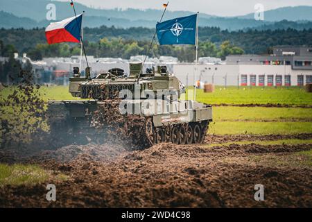 NATO-Panzer der Deutsche machte Leopard 2 A7 während der Kriegsspieloperation vor tschechischer Flagge und NATO-Flagge auf einem matschigen Feld in Europa. Stockfoto