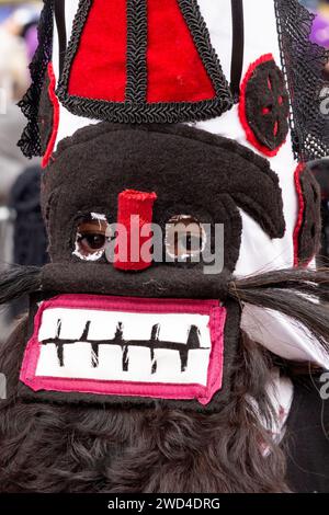 Detailansicht der maskierten Kukeri-Tänzerin mit markanter, aufgestickter schwarzer und roter Maske beim Surva Kukeri Festival in Pernik, Bulgarien Stockfoto