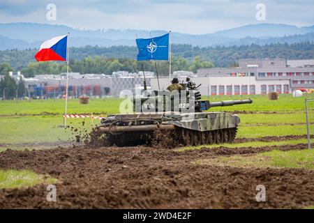 T72 Tank (M4 CZ Variantennummer 029) fährt während einer Demonstrationsübung auf einem schlammigen Feld vor NATO- und Tschechischen Flaggen. Stockfoto