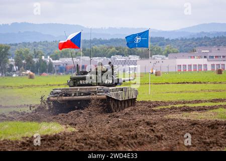 T72 Tank (M4 CZ Variantennummer 029) fährt während einer Demonstrationsübung auf einem schlammigen Feld vor NATO- und Tschechischen Flaggen. Stockfoto