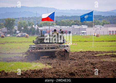 T72 Tank (M4 CZ Variantennummer 029) fährt während einer Demonstrationsübung auf einem schlammigen Feld vor NATO- und Tschechischen Flaggen. Stockfoto