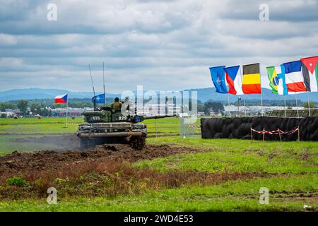 T72 Tank (M4 CZ Variantennummer 029) fährt während einer Demonstrationsübung auf einem schlammigen Feld vor NATO- und Tschechischen Flaggen. Stockfoto