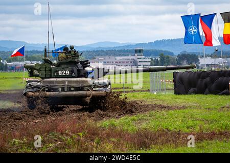 T72 Tank (M4 CZ Variantennummer 029) fährt während einer Demonstrationsübung auf einem schlammigen Feld vor NATO- und Tschechischen Flaggen. Stockfoto