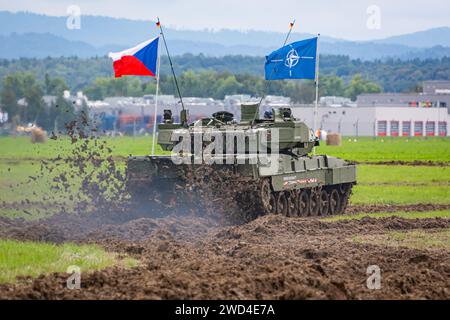 T72 Tank (M4 CZ Variantennummer 029) fährt während einer Demonstrationsübung auf einem schlammigen Feld vor NATO- und Tschechischen Flaggen. Stockfoto