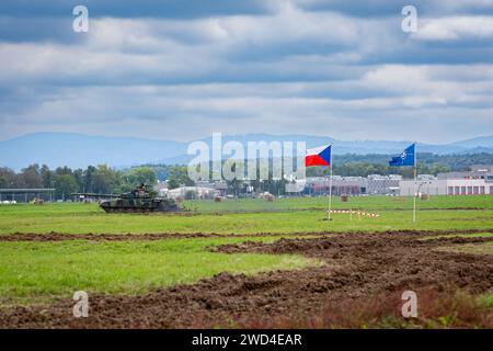 T72 Tank (M4 CZ Variantennummer 029) fährt während einer Demonstrationsübung auf einem schlammigen Feld vor NATO- und Tschechischen Flaggen. Stockfoto