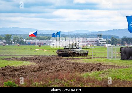 T72 Tank (M4 CZ Variantennummer 029) fährt während einer Demonstrationsübung auf einem schlammigen Feld vor NATO- und Tschechischen Flaggen. Stockfoto