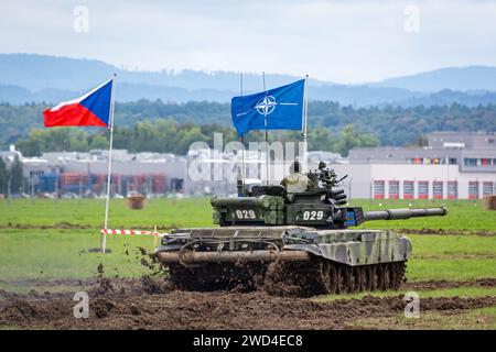 T72 Tank (M4 CZ Variantennummer 029) fährt während einer Demonstrationsübung auf einem schlammigen Feld vor NATO- und Tschechischen Flaggen. Stockfoto