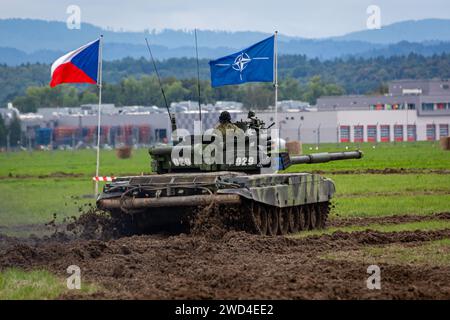 T72 Tank (M4 CZ Variantennummer 029) fährt während einer Demonstrationsübung auf einem schlammigen Feld vor NATO- und Tschechischen Flaggen. Stockfoto