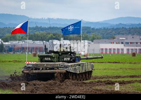 T72 Tank (M4 CZ Variantennummer 029) fährt während einer Demonstrationsübung auf einem schlammigen Feld vor NATO- und Tschechischen Flaggen. Stockfoto