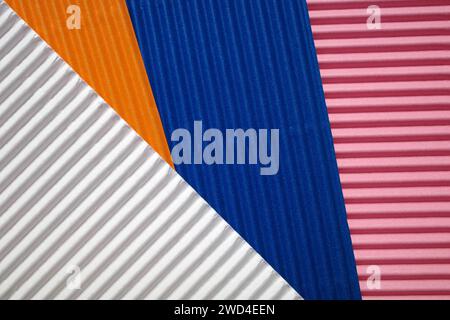 Horizontal und diagonal geriffelte Pappe mit den Farben Pink, weiß, Orange und Blau. Als Hintergrund gedacht Stockfoto