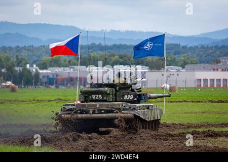 T72 Tank (M4 CZ Variantennummer 029) fährt während einer Demonstrationsübung auf einem schlammigen Feld vor NATO- und Tschechischen Flaggen. Stockfoto