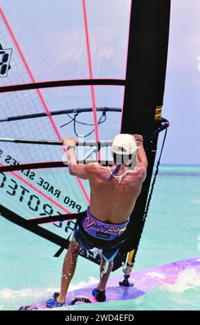 Ein junger Mann beim Windsurfen (Boardsegeln) in den Gewässern vor Aruba CA. Mitte der 1990er Jahre Bitte schreiben Sie dem Fotografen Joan Iaconetti zu. Stockfoto