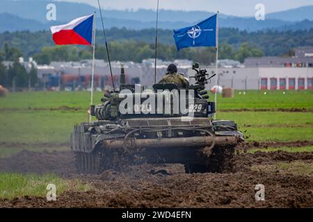 T72 Tank (M4 CZ Variantennummer 029) fährt während einer Demonstrationsübung auf einem schlammigen Feld vor NATO- und Tschechischen Flaggen. Stockfoto