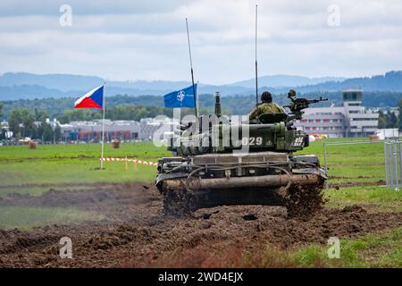 T72 Tank (M4 CZ Variantennummer 029) fährt während einer Demonstrationsübung auf einem schlammigen Feld vor NATO- und Tschechischen Flaggen. Stockfoto