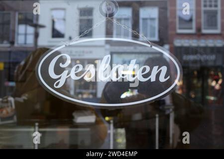 Geschlossenes Schild, das an einer Kette in der Tür eines niederländischen Ladens hängt. Gesloten ist Niederländisch für geschlossen. Stockfoto