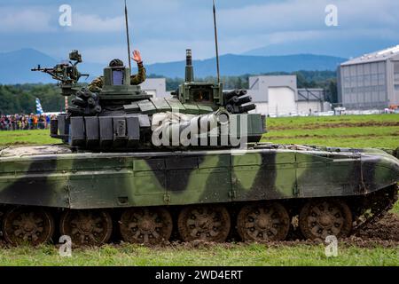 T72 Tank (M4 CZ Variantennummer 029) fährt während einer Demonstrationsübung auf einem schlammigen Feld vor NATO- und Tschechischen Flaggen. Stockfoto