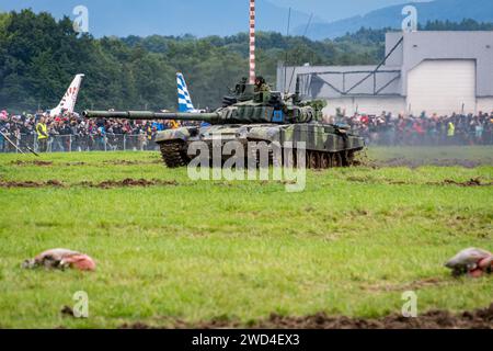 T72 Tank (M4 CZ Variantennummer 029) fährt während einer Demonstrationsübung auf einem schlammigen Feld vor NATO- und Tschechischen Flaggen. Stockfoto