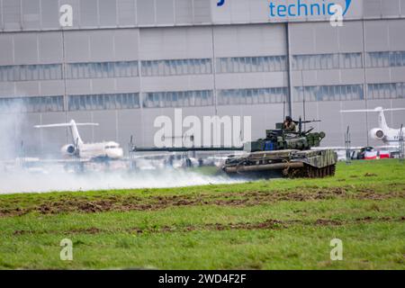 T72 Tank (M4 CZ Variantennummer 029) fährt während einer Demonstrationsübung auf einem schlammigen Feld vor NATO- und Tschechischen Flaggen. Stockfoto