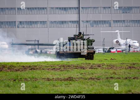 T72 Tank (M4 CZ Variantennummer 029) fährt während einer Demonstrationsübung auf einem schlammigen Feld vor NATO- und Tschechischen Flaggen. Stockfoto