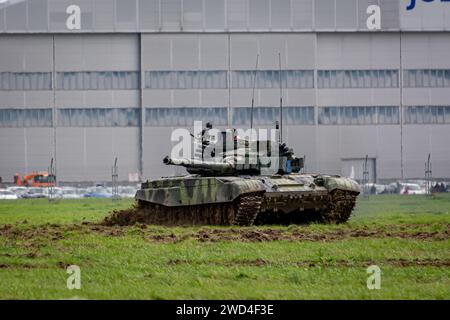 T72 Tank (M4 CZ Variantennummer 029) fährt während einer Demonstrationsübung auf einem schlammigen Feld vor NATO- und Tschechischen Flaggen. Stockfoto