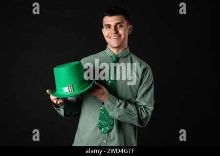 Glücklicher junger Mann mit grünem Hut auf dunklem Hintergrund. St. Patrick's Day Stockfoto
