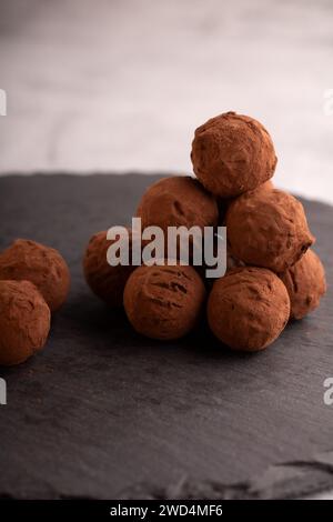 Fotografie mit hausgemachten Trüffeln aus dunkler Schokolade, verziert mit Kakaopulver. Diese optisch ansprechende Anordnung spiegelt den Reichtum von coc wider Stockfoto