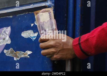 Dhaka, Bangladesch. Januar 2024. Ein Bushelfer hält Banknoten, die Taka in der Nähe einer Straße in Dhaka auf Passagiere wartet. (Kreditbild: © MD Mehedi Hasan/ZUMA Press Wire) NUR REDAKTIONELLE VERWENDUNG! Nicht für kommerzielle ZWECKE! Stockfoto