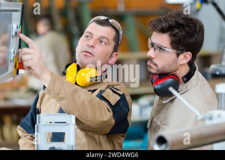 Arbeiter und Auszubildender, der eine Maschine in einer Fabrik bedient Stockfoto