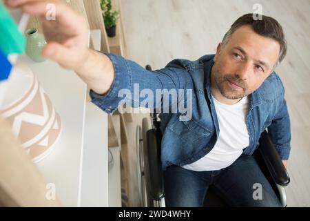 Mitarbeiter im Rollstuhl, der ein Buch erreicht Stockfoto