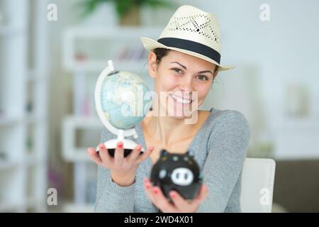 Eine Frau, die eine Schweinebank mit Weltkugel hält Stockfoto