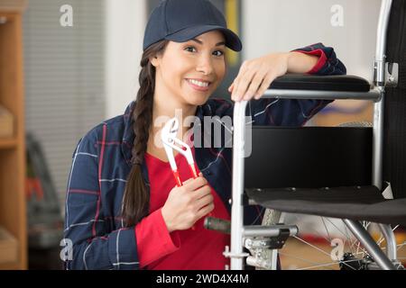 Weibliche Mechanikerin, die einen Rollstuhl repariert Stockfoto