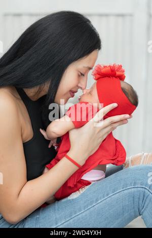 Junge Latina-Frau, die ihre Nase an die Nase ihres neugeborenen Babys legt, während sie ihr neugeborenes Mädchen anhält und zärtlich anstarrt. Stockfoto