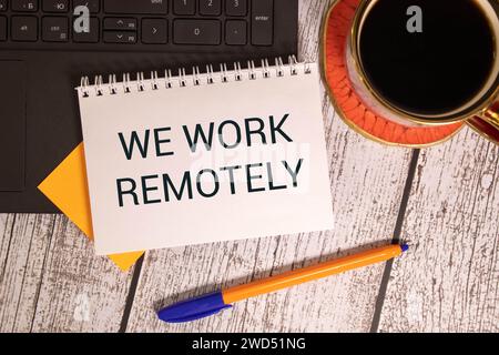 WORK REMOTELY text on a sticky with pen on the wooden background. Stock Photo