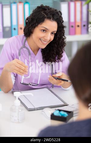 Freundliche junge Ärztin spricht Patient Stockfoto