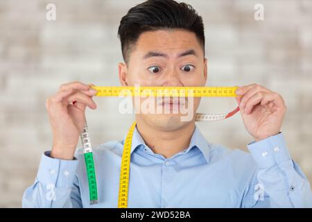 Mann hält Maßband vor seinem Gesicht Stockfoto