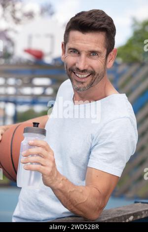 Mann trinkt Wasser aus der Flasche auf dem Basketballfeld Stockfoto