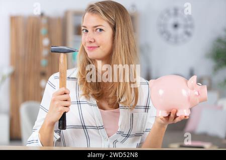 Die junge lächelnde Frau bricht eine Porzellanschweinbank Stockfoto