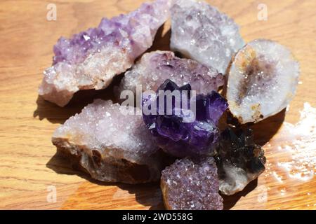 Wunderschöner lila Druzy mit Amethyst-Kristallen auf einem nassen hölzernen Hintergrund. Magische Halbedelsteine. Stockfoto