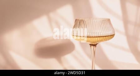 Glas mit Weißwein auf hellem Hintergrund mit Schatten Stockfoto