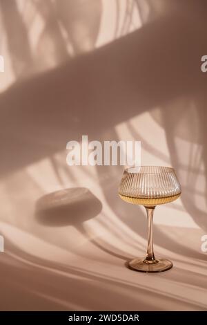 Glas mit Weißwein auf hellem Hintergrund mit Schatten Stockfoto